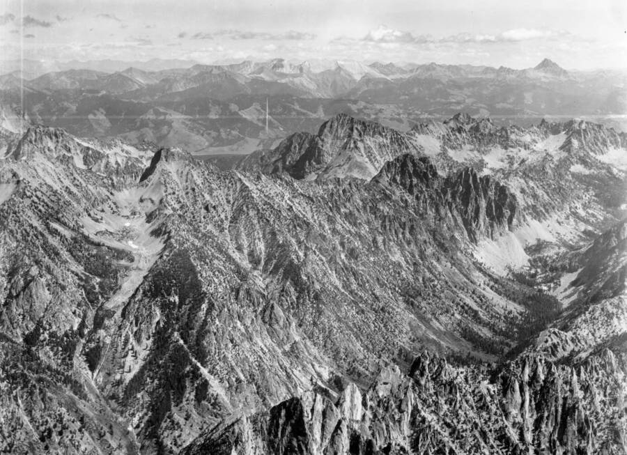 Photo caption: 'Peak in extreme upper right is Castle Peak in the White Cloud Peaks which show in the distance. The main drainage in the foreground is Baron Creek. The tributary coming into Baron Creek at the left is Mooluck Creek. The peak with the dark shadow at the head of Mooluck Creek is Baron Peak. The valley in the distance beyond Baron Peak is Stanley Basin. Just beyond and right of Baron Peak is the head of Fishhook Creek, while over the saddle north of Baron Peak is the head of the North Fork of Baron Creek.'