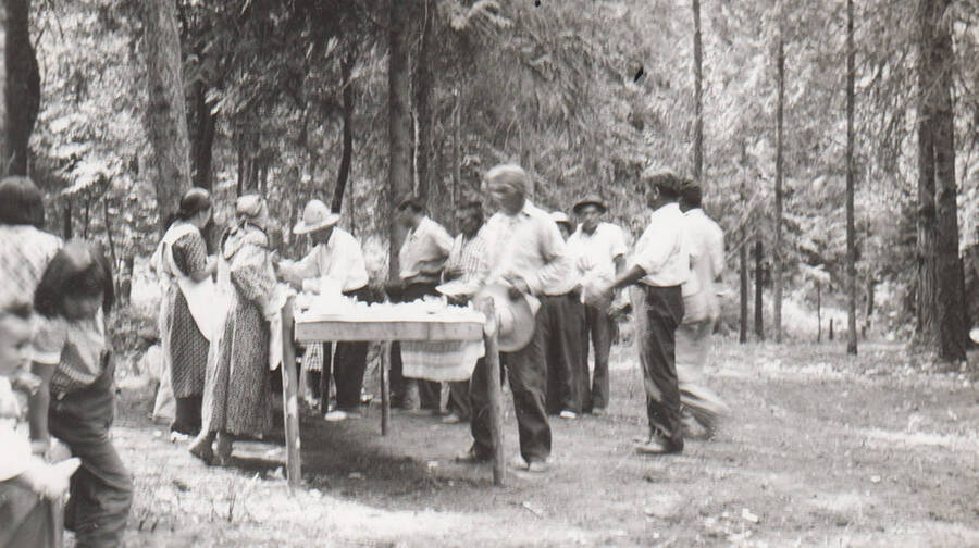 Photo caption: 'Everyone gathers at the picnic grounds to again celebrate having a good community garden in 1938.' This image is part of a report regarding farm organizations among tribes in Northern Idaho and the CCC-Indian Division.