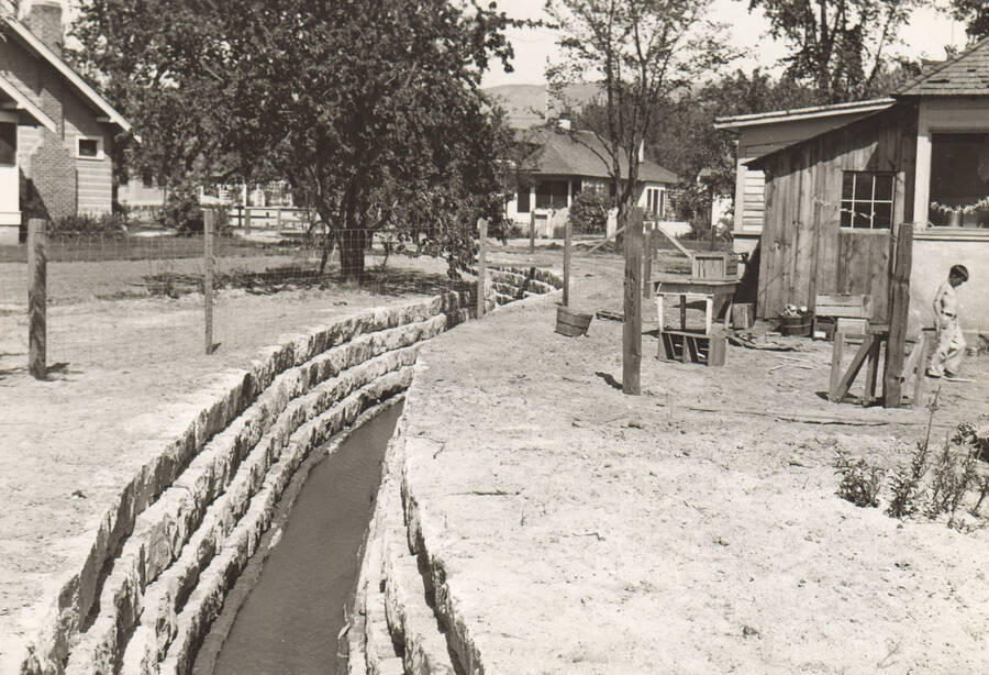 A view of Sand Creek after a rip-rap control channel was installed by WPA. House on both sides. Note: This image is part of a Work Progress Administration publicity series.