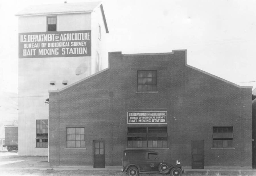 Photo text: 'Exterior view of the Bait Mixing Station quarters. The metal building on the left houses the storage bins and machinery.'