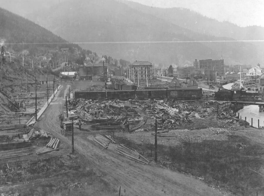 Wallace after the fire known as the Big Burn. Photo text: 'Taken were the fire was at its most fierce. On this terrace at Wallace every house was burned and about 200 in all. In the foregrounds a Mining Supply House, Probably the largest losers in Wallace from the fire.'