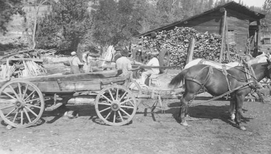 Photo caption: 'Indians haul and saw wood for winter use. Mark Arthur place, Kamiah.' This image is part of a report regarding farm organizations among tribes in Northern Idaho and the CCC-Indian Division.
