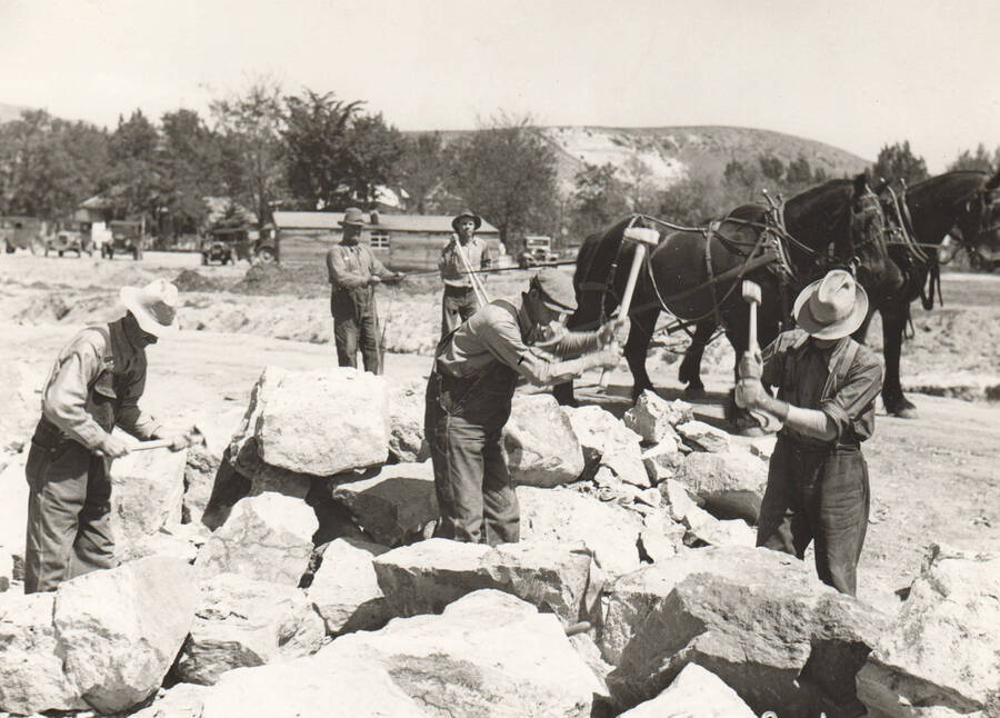 Men brake down materials for rip-rap construction of Sand Creek control channel. A WPA project. Note: This image is part of a Work Progress Administration publicity series.
