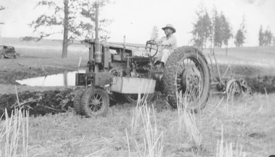 Photo caption: 'Farm Chapter President David Arthur, leases some Tribal Lands and here he is plowing with his tractor.' This image is part of a report regarding farm organizations among tribes in Northern Idaho and the CCC-Indian Division.