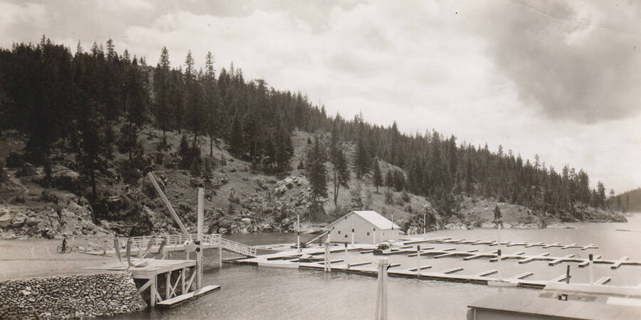 Photo text: 'Coeur d'Alene's municipal yacht basin - one of the few such city-owned facilities in the west. Undertaken as a WPA project the yacht basin has an initial unit of 60 moorage slips. An attendant is on duty 24 hours daily. A modern boat lift or hoist, with electric motor, boom and canvas belting slings, permits pf raising or lowering a boat to [the lake] in a few minutes. There is enough additional room in the yacht basin, behind the breakwater, for another 350 to 400 boats. Project cost WPA $8,040 and sponsors $3,640.' Note: This image is part of a Work Progress Administration publicity series.