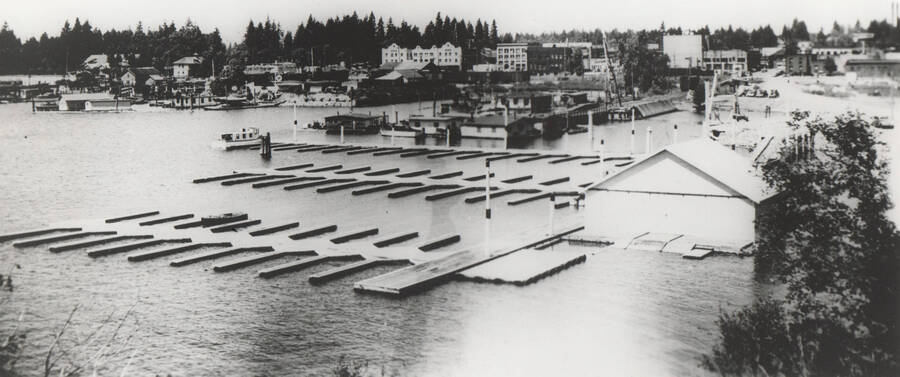 Photo text: 'Looking down on the Coeur d'Alene, Idaho yacht basin... Constructed with WPA labor. In the distance are old railroad docks and those of boat transportation lines, some of which it is hoped will be eliminated in the City's plans to streamline the lake front. Foreground leads out to main protected basin where a thousand-foot boon extends from the mainland, connecting with other breakwaters, and creating enough room...' Note: This image is part of a Work Progress Administration publicity series.