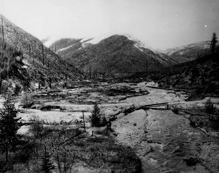 Photo text: 'A burned watershed. The denuded mountain sides of the Big Creek watershed burned in 1920 do not tend to retard the runoff from the melting snow. Spring freshets which sweep the valley deposit silt, gravel, and down timber along the bottoms, causing unforeseen changes in the stream channel.'