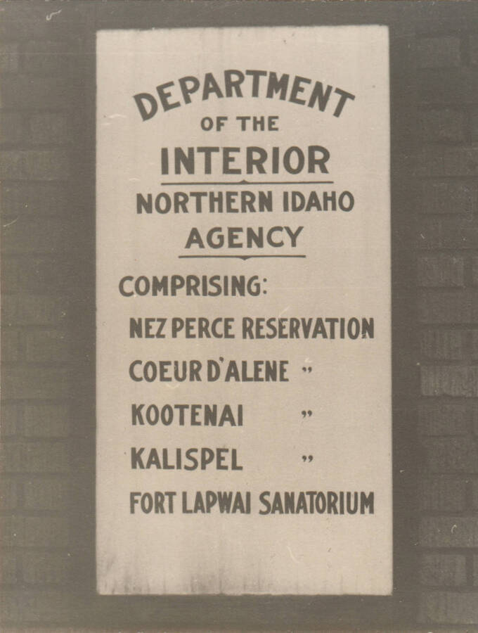 A sign for the Department of the Interior Northern Idaho Agency hangs on a brick building. Note: This image is part of a narrative pictoral report to accompany quarterly enrollee program report.