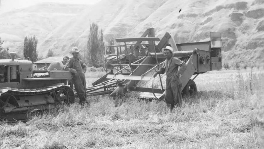 Photo caption: 'Alex Pinkham and his new harvesting outfit. Tractor and one man harvester.' This image is part of a report regarding farm organizations among tribes in Northern Idaho and the CCC-Indian Division.