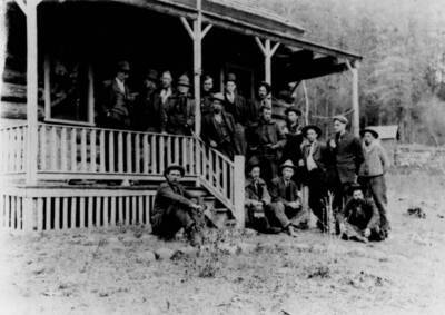 Photo text: 'Major Feen sitting on bottom step (with tie.)' A list of the attendees was compiled on the back of the image. This was scanned with the image.