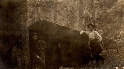 Photo text: 'Cabin on claim of Paul Leuschel, a bank clerk of Moscow, Idaho, at time of location. Was in contest with State of Idaho, and in all probability his rights will survive that of the State. He is now cashier of the Wallace National Bank, at Wallace, Idaho. His residence has never prevented his continuous presence at his employment in the bank. Note the height of the roof against which a man is leaning. Photo taken in fall of 1905. Leuschel located October 25, 1901. He is a man with a family who have never seen their 'Home' in Marble Creek. After holding the claim from 1901 or 1911 under his own name, on November25, 1911, he filed a soldier's additional claim on the land in the name of Henery H. Holstein. Final certificate was issued August 8, 1914. He declares before the Idaho Legislative Homestead Commission that he desired the land for a home. His assertion is not borne out by his subsequent acts.' Note: Marble Creek region homesteads at this time were often part of a homesteads fraud being documented by the US Forest Service.