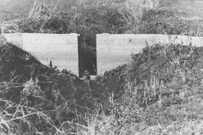 Checking the small damn in an irrigation ditch on the Fort Lapwai Sanatorium grounds. Note: This image is part of a narrative pictoral report to accompany quarterly enrollee program report.