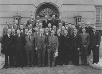 Men pose for a photograph on the stairs in front of a building.