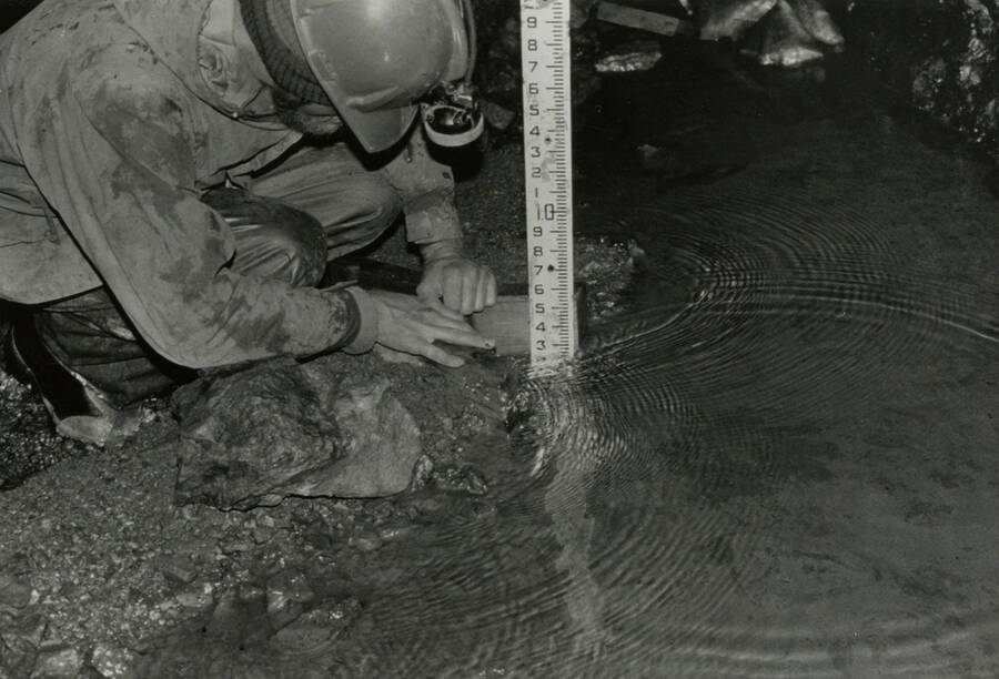 An individual measuring water levels in a mine.