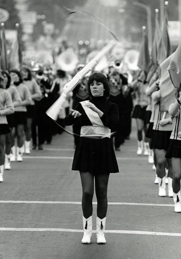 A drill team member spinning a replica rifle during a Homecoming parade.