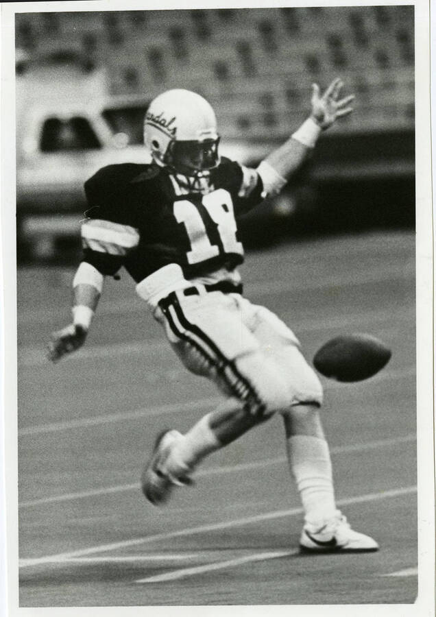 Idaho football player, wearing jersey number 18, seeming to kick the ball.