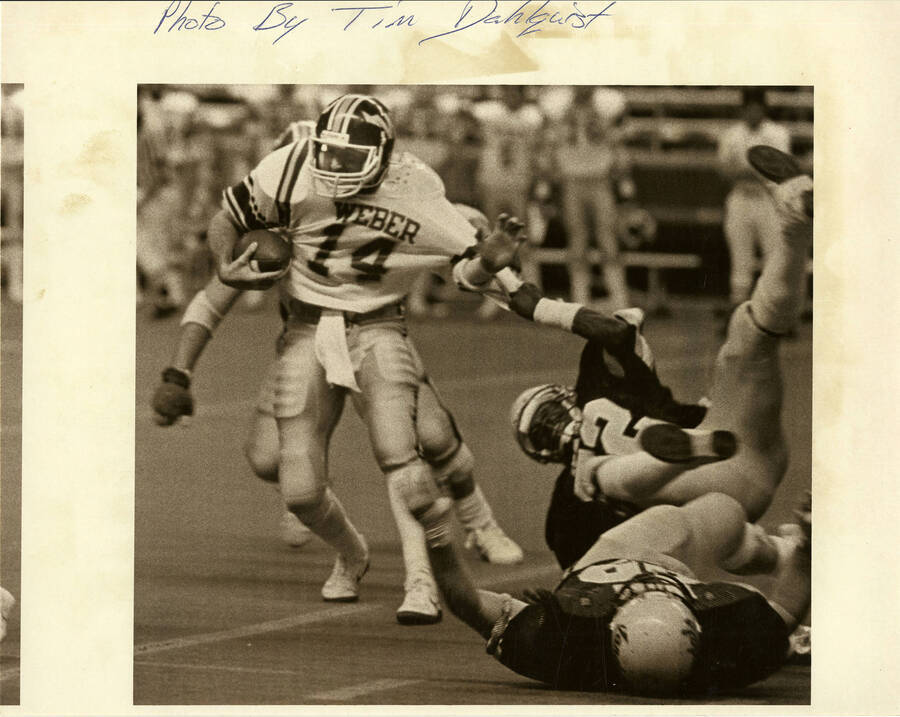 Idaho football player, Weber number 14, being pulled by his jersey by an opposing team player.