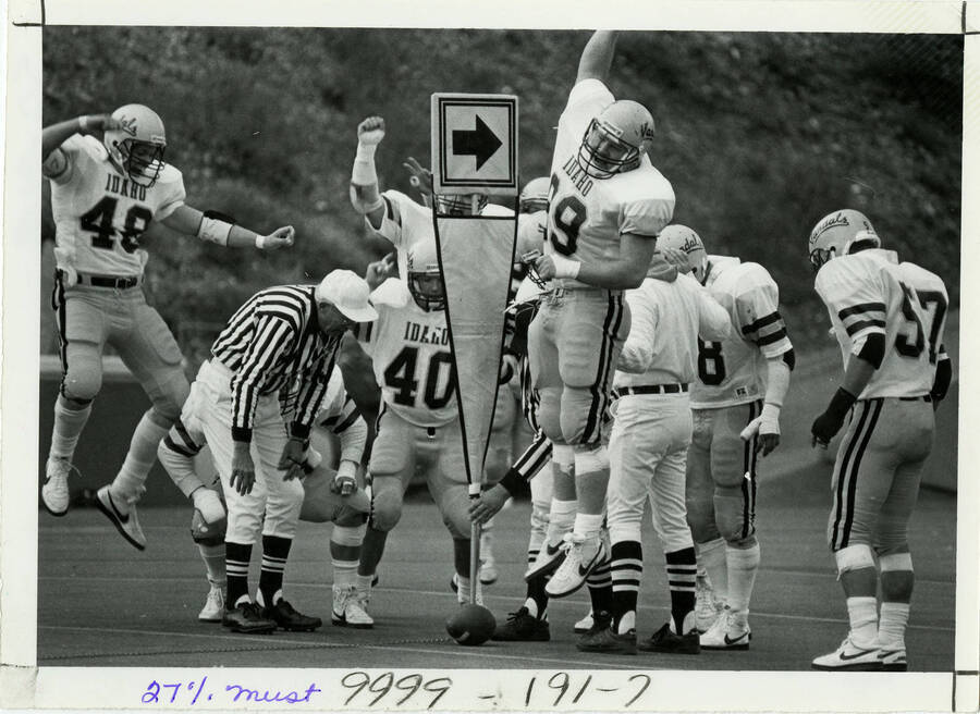 Referees examine Idaho fourth down. Idaho football players  No. 48 and No. 99 cheering. #48 Mike Cox (normally 45). #40 Don McCanna. #99 Kord Smith. #8 Ernest Sanders. #57 Dave Parker. 9/30 Arg. pg. 7.