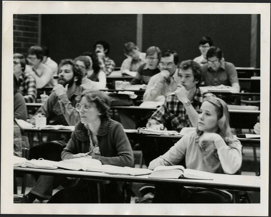 Students taking notes at desks in a classroom.