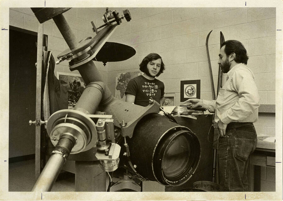 Two men talking in a room with astronomy equipment.