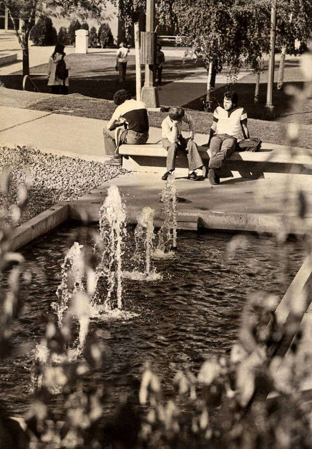 Three students sitting by a fountain in front of the University Classroom Center (now the Teaching and Learning Center).