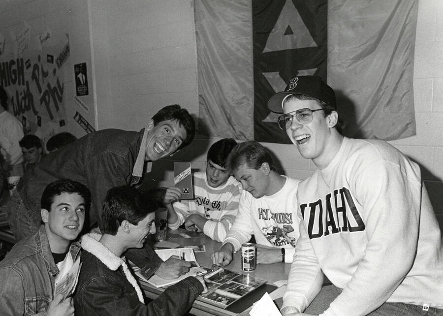 Delta Chi Fraternity brothers at a booth looking at photographs.