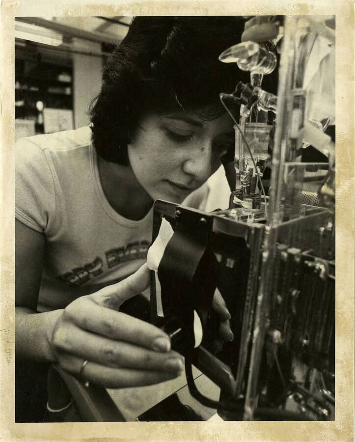 Woman  looking through scientific equipment, possibly a microscope.