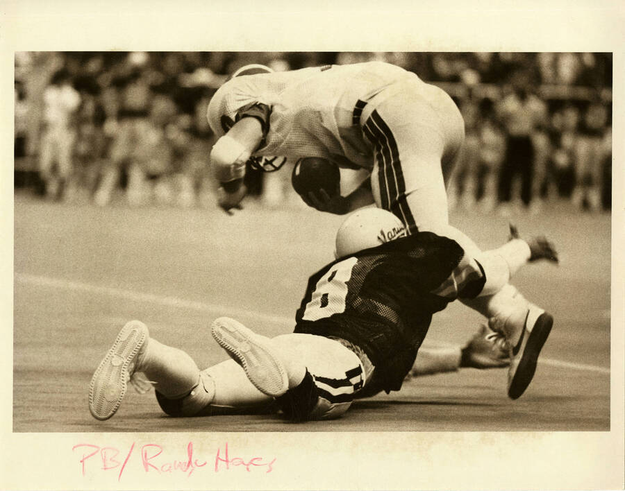 Idaho football player, wearing jersey number 8, tackling opposing player with the football.