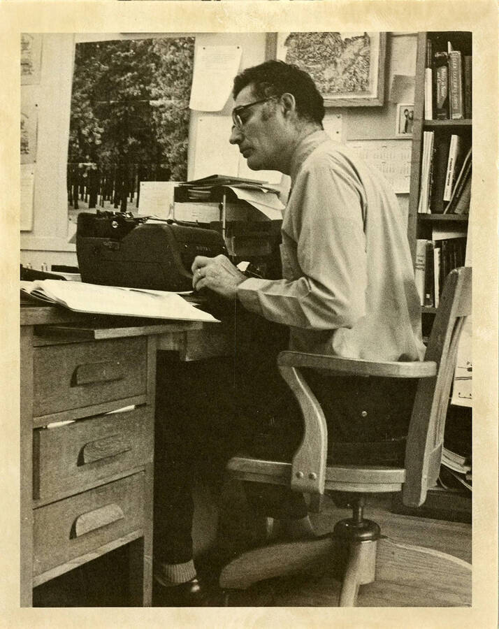 H. Sydney Duncombe, Political Science Professor, sitting at a desk looking at the papers on his desk.