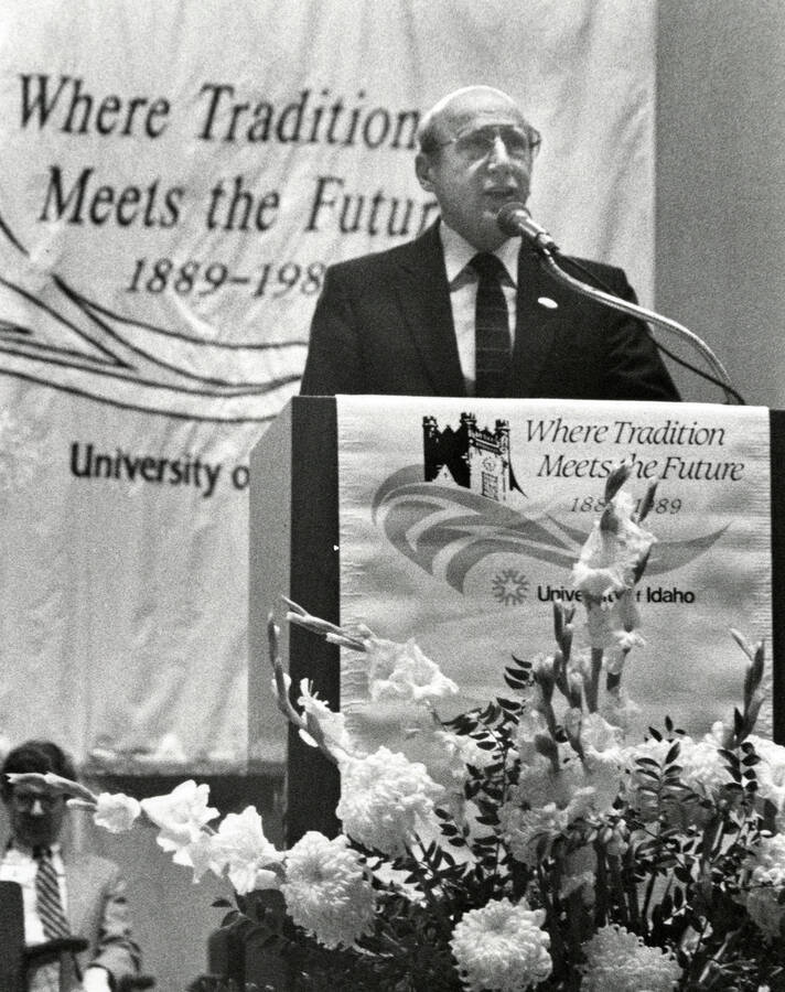 University of Idaho Centennial. Robert Gibb speaking at a podium in front of a banner reading ""Where Tradition Meets the Future 1889-1989.""