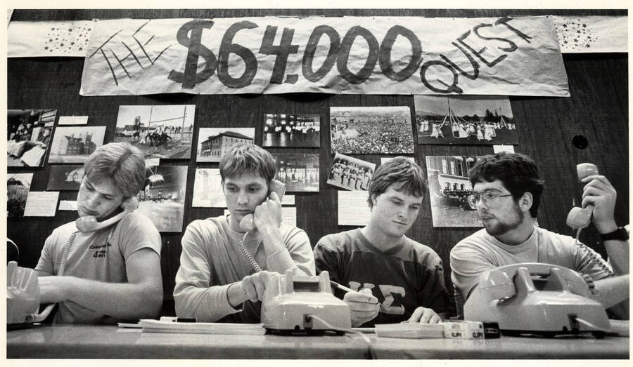 Four students working the alumni phonathon beneath a banner that reads 'The $64,000 Quest.'