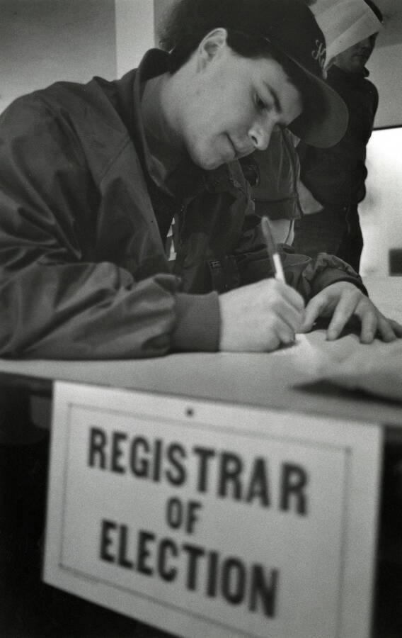 A student writing near a sign that reads ""Registrar of Election.""