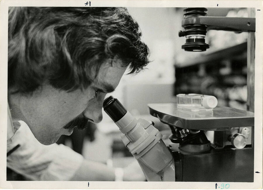 Man looking through a binocular microscope.