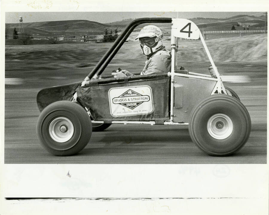 Man racing in an engineering efficiency vehicle with the number 4. Label on the side of the vehicle reads: ""4 cycle engine - Briggs & Stratton - Milwaukee Wisconsin  U.S.A. - most respected name in power.""