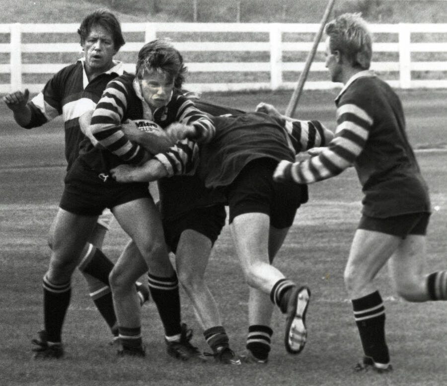 Four students playing rugby outdoors.