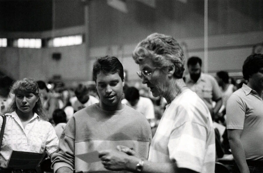 A faculty member helping a student with their registration in the Kibbie Dome.