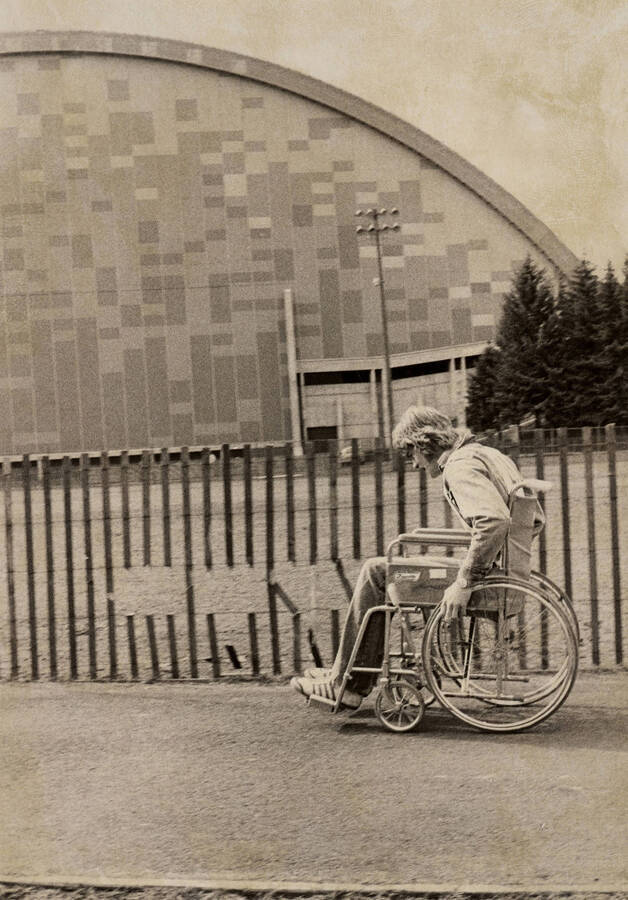 A student in a wheelchair passing in front of the Kibbie Dome during the Special Olympics.