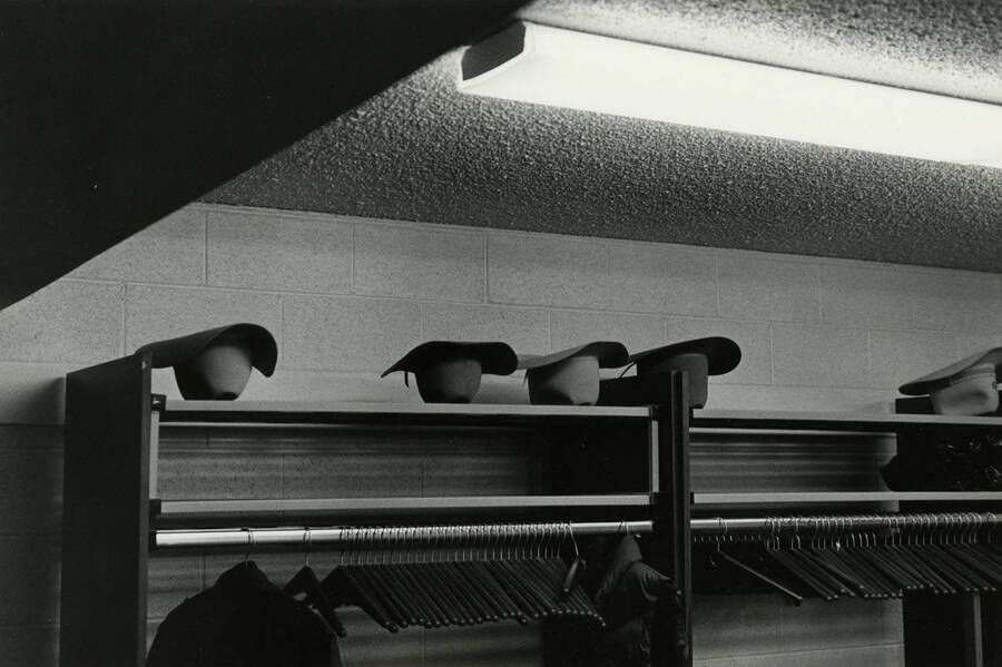 A few cowboy hats on a shelf above a coat rack in the Salmon, Idaho Town Hall building during a meeting. Caption on back reads ""Salmon Town Hall meeting.""