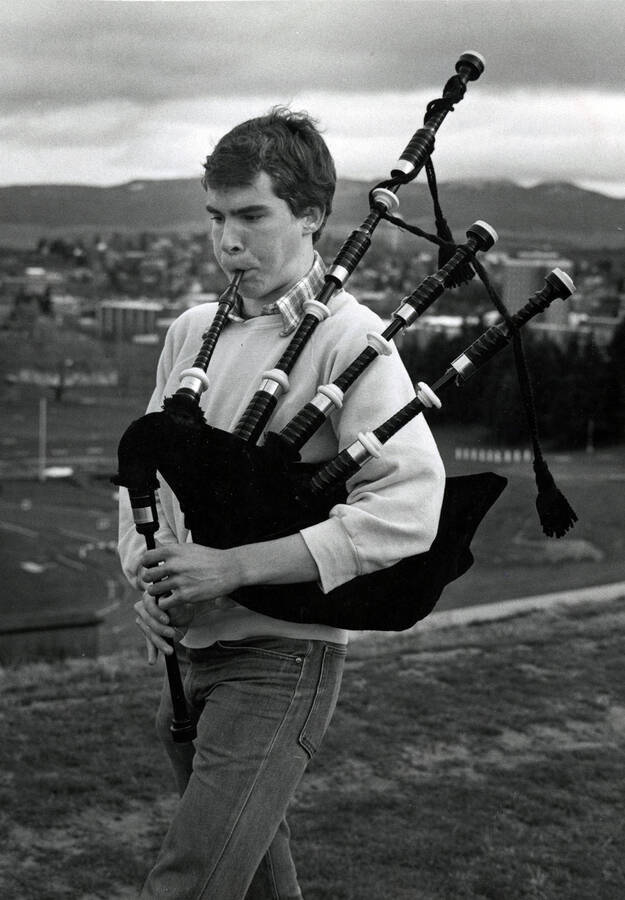 A student playing bagpipes outside.