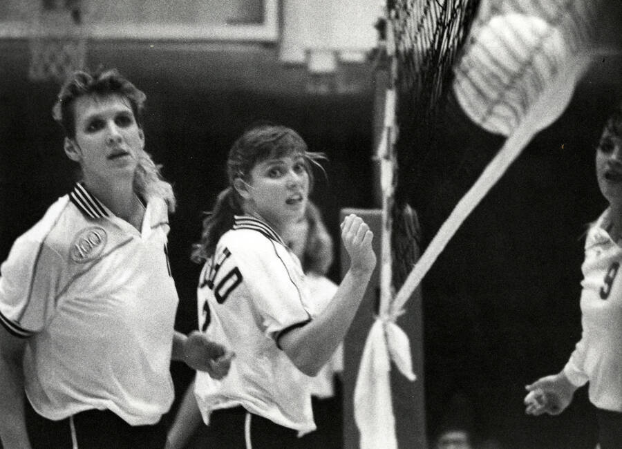 Two students watch the ball hit the net during a volleyball game.
