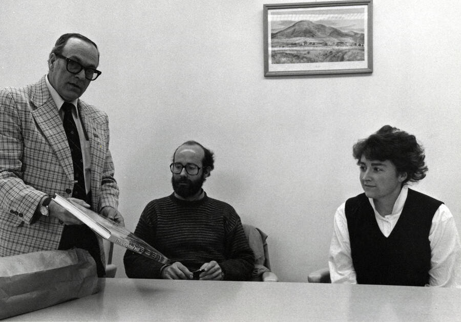 Keith Petersen (center), author of ""This Crested Hill: An Illustrated History of the University of Idaho,"" sits with two other people as they look at a copy of the book. The book was released by the University of Idaho Press in 1987.