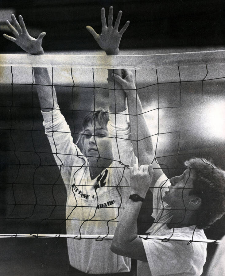 A volleyball player being measured up against the height of the net.