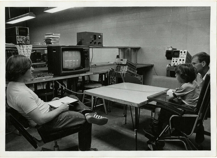 Two men teaching a boy using television.
