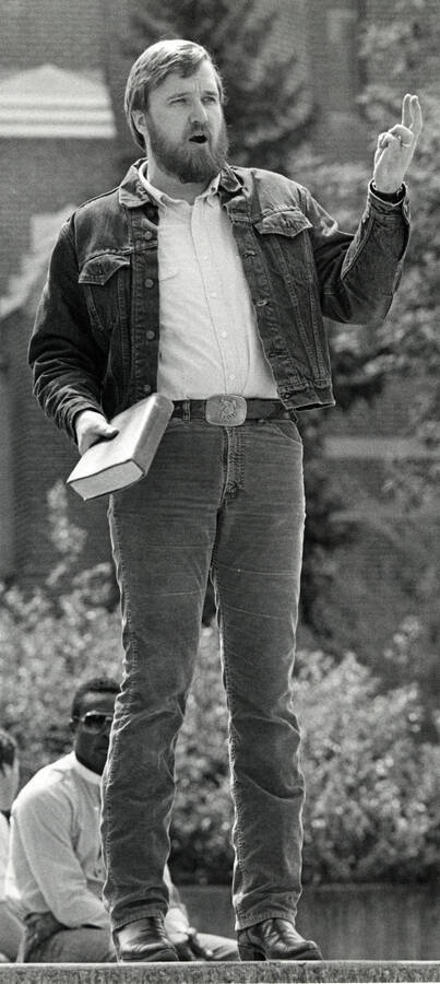 Doug Wilson holding a Bible and appearing to count aloud on his fingers.