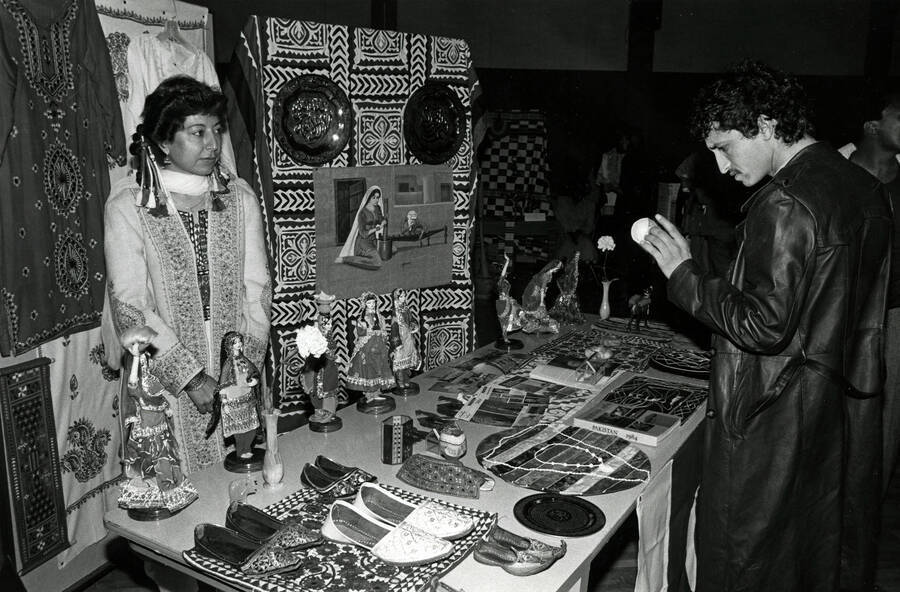 A student looks at various items on a table at an international event, possibly ""Cruise the World.""