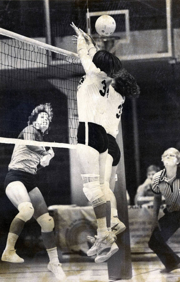 Two Vandals volleyball players jumping to block a shot during a game.