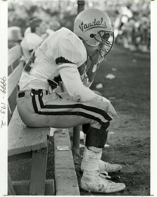 #94 TE. Chris Slater sitting on a bench with his hand on his face out of frustration of tiredness.