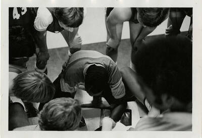 Basketball players huddled around an instructor.