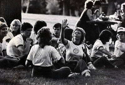 The U of I band's audience of students sits in the grass in East City Park.