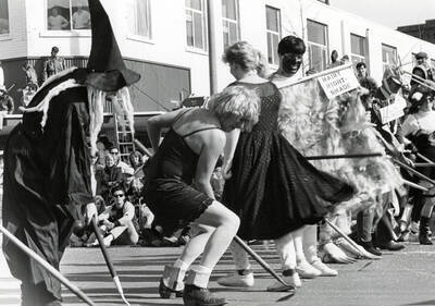 People in costume holding garden tools during a parade on the corner of Main Street and 3rd.